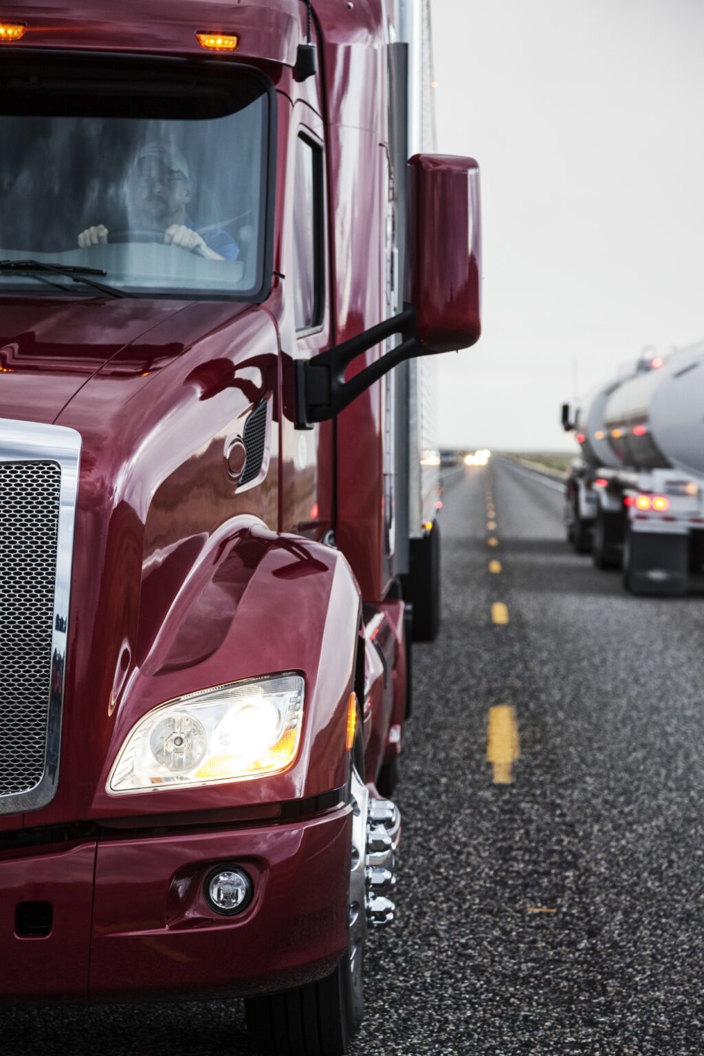 Close up view of the cab and driver of a commercial truck on the highway.